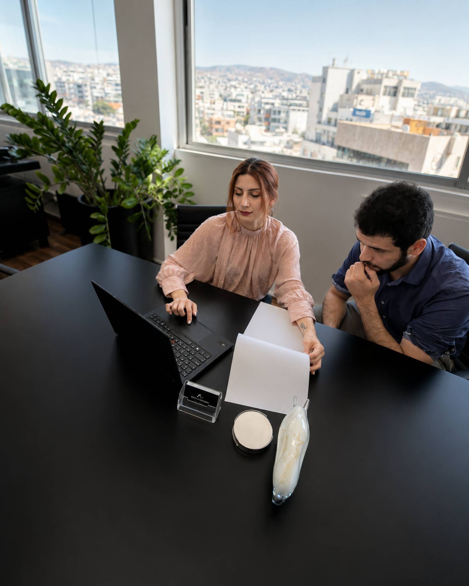 Two Nikita & Partners professionals reviewing a document at a laptop in the firm's Limassol office